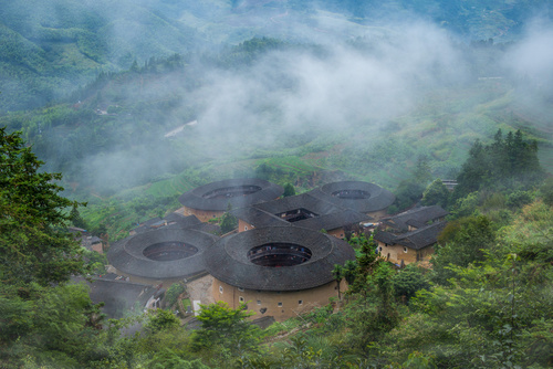 aerial view of Tianluokeng Tulou cluster with mist